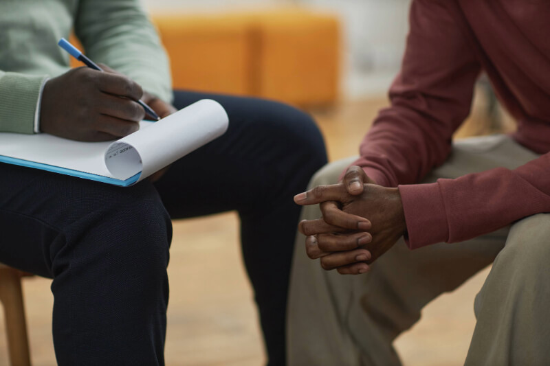 A mental health professional meeting with an adult client at home, illustrating the ACT Assertive Community Treatment model.
